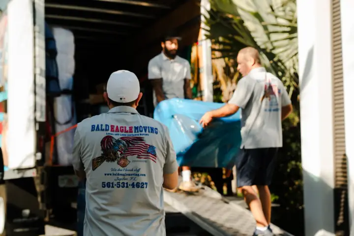 Bald Eagle Moving crew moving a specialty item from a branded truck